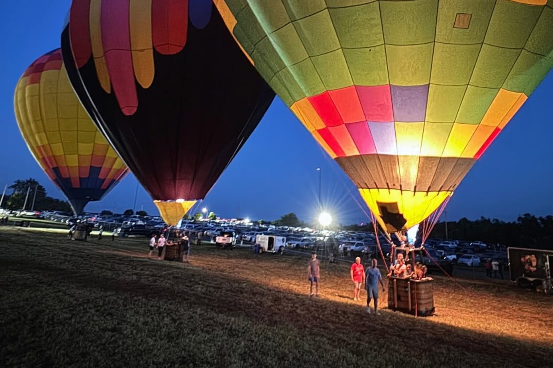 Envelopes lit from inside on a night glow, crew still standing in the grass