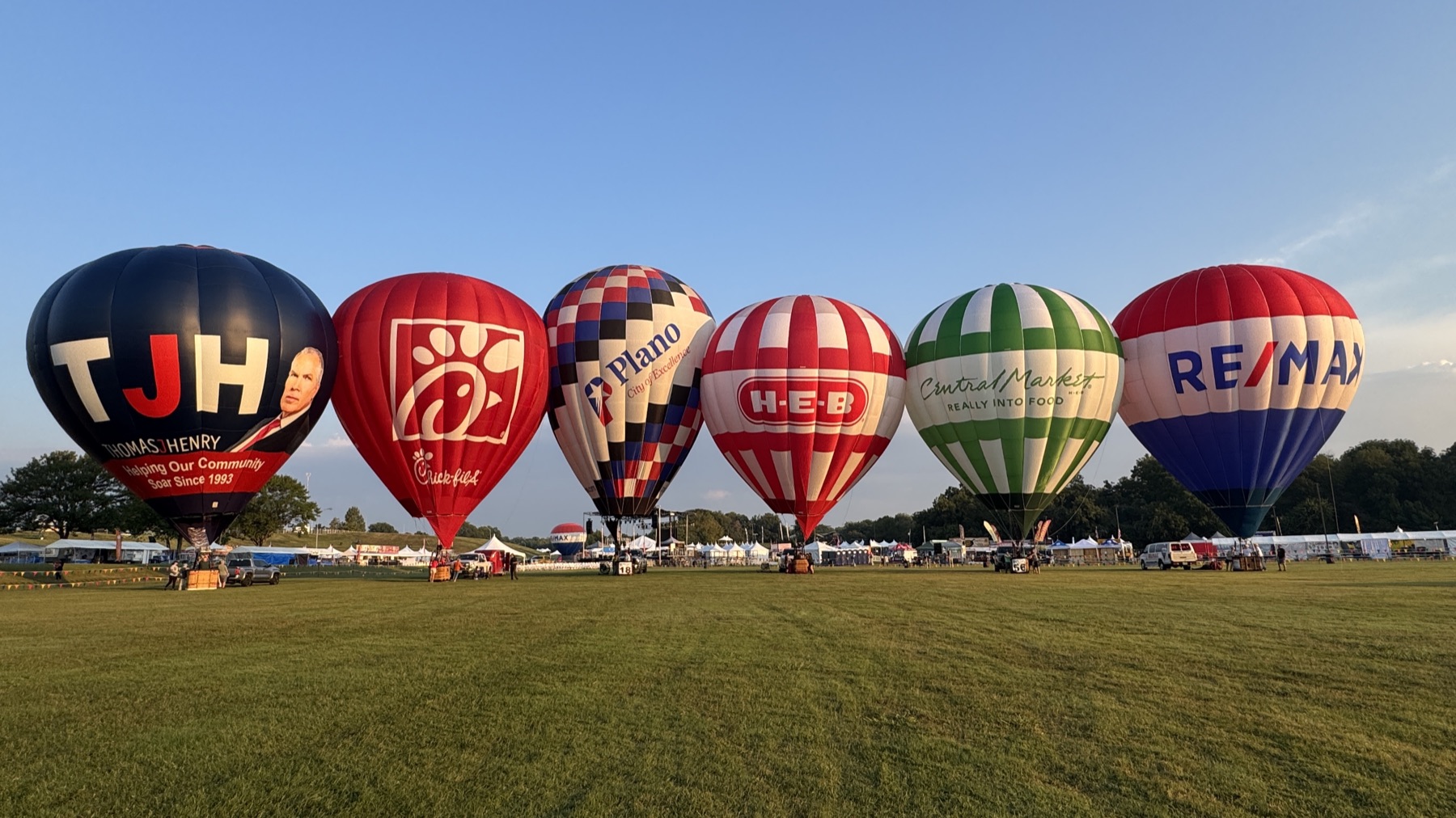 Special shape and sponsor balloons standing on a festival field